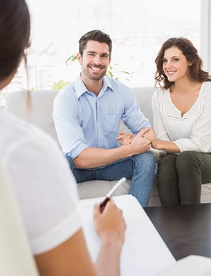 Couple Smiling During Family Counseling Session with Therapist Taking Notes